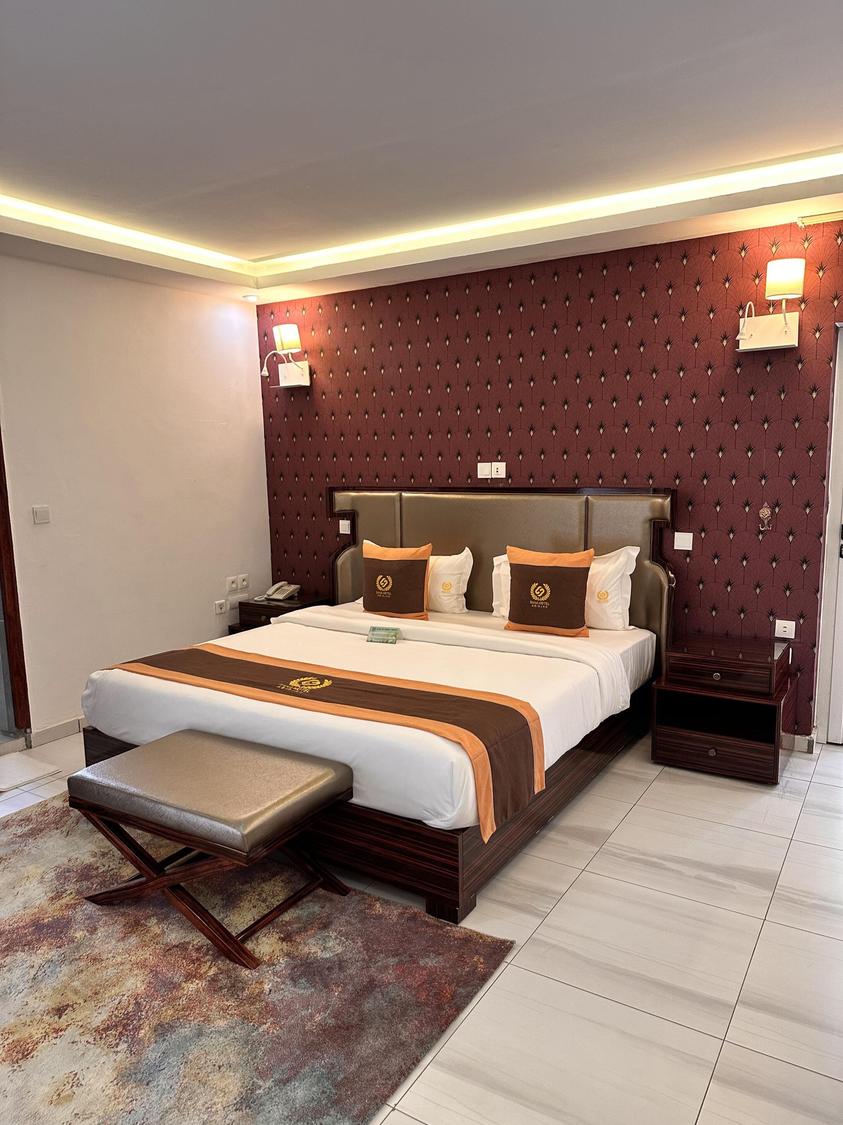 Una habitación de hotel moderna con una cama grande, una mesita de noche y un buró.