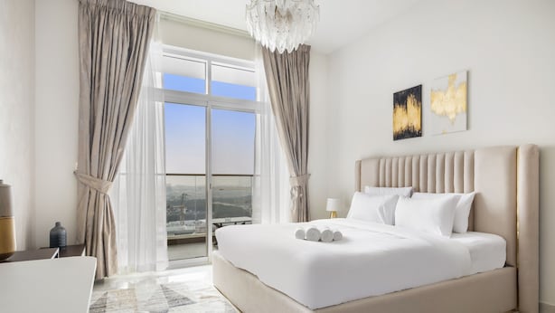 A modern hotel room with a large bed, a desk, and a view of the city. - Premium Studio near Butterfly Garden w/ Pool & Gym (Dubai)