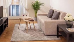 Un salon moderne avec un canapé, une table basse, un meuble pour la télévision et une plante en pot.