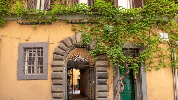 A historic building with an arched entrance, a green door, and a window with bars. - Daplace - Mirta Apartment (Roma)