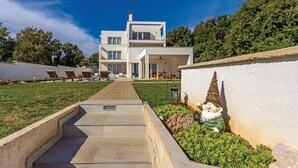 Une maison moderne à deux étages, avec un chemin pavé menant à l’entrée.