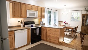 A kitchen with wooden cabinets, a microwave, a stove, and a dishwasher. - The Coastal Cottage | Walk to Pemaquid Beach | Fire Pit & Family-Friendly Retreat (Bristol)