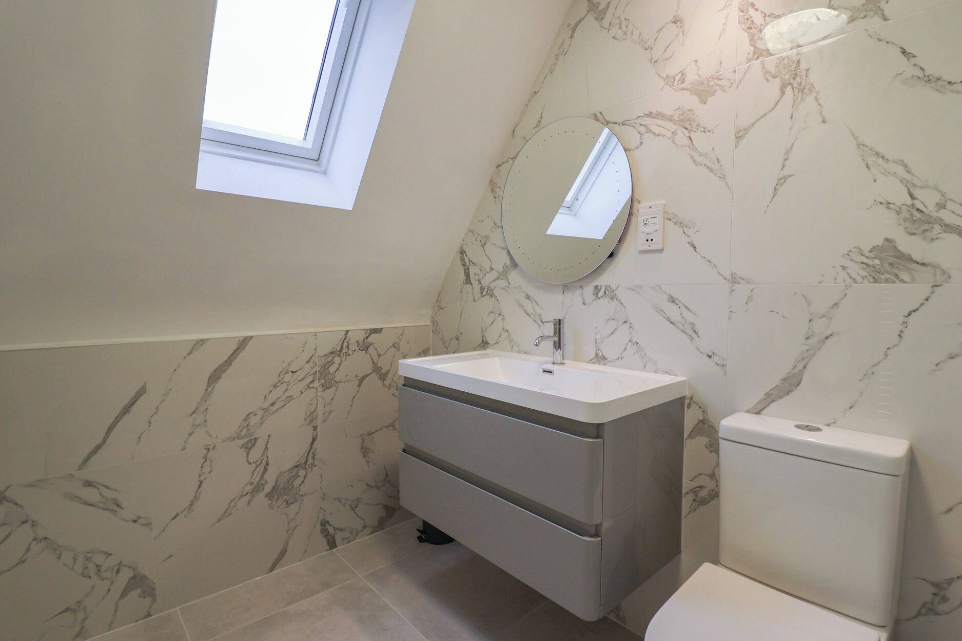 A bathroom with a vanity, sink, mirror, and toilet.