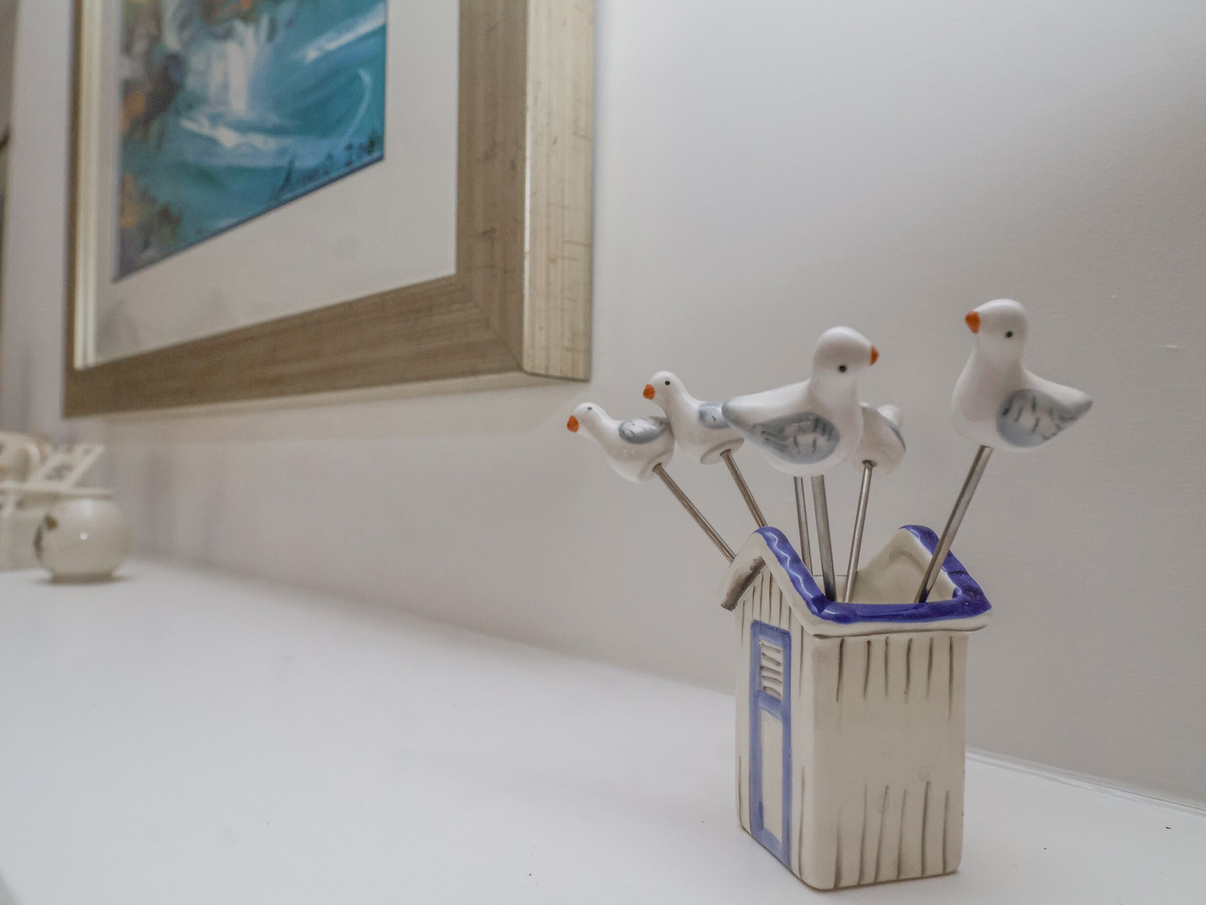 Un recipiente in ceramica con manici a forma di uccello su una superficie bianca.