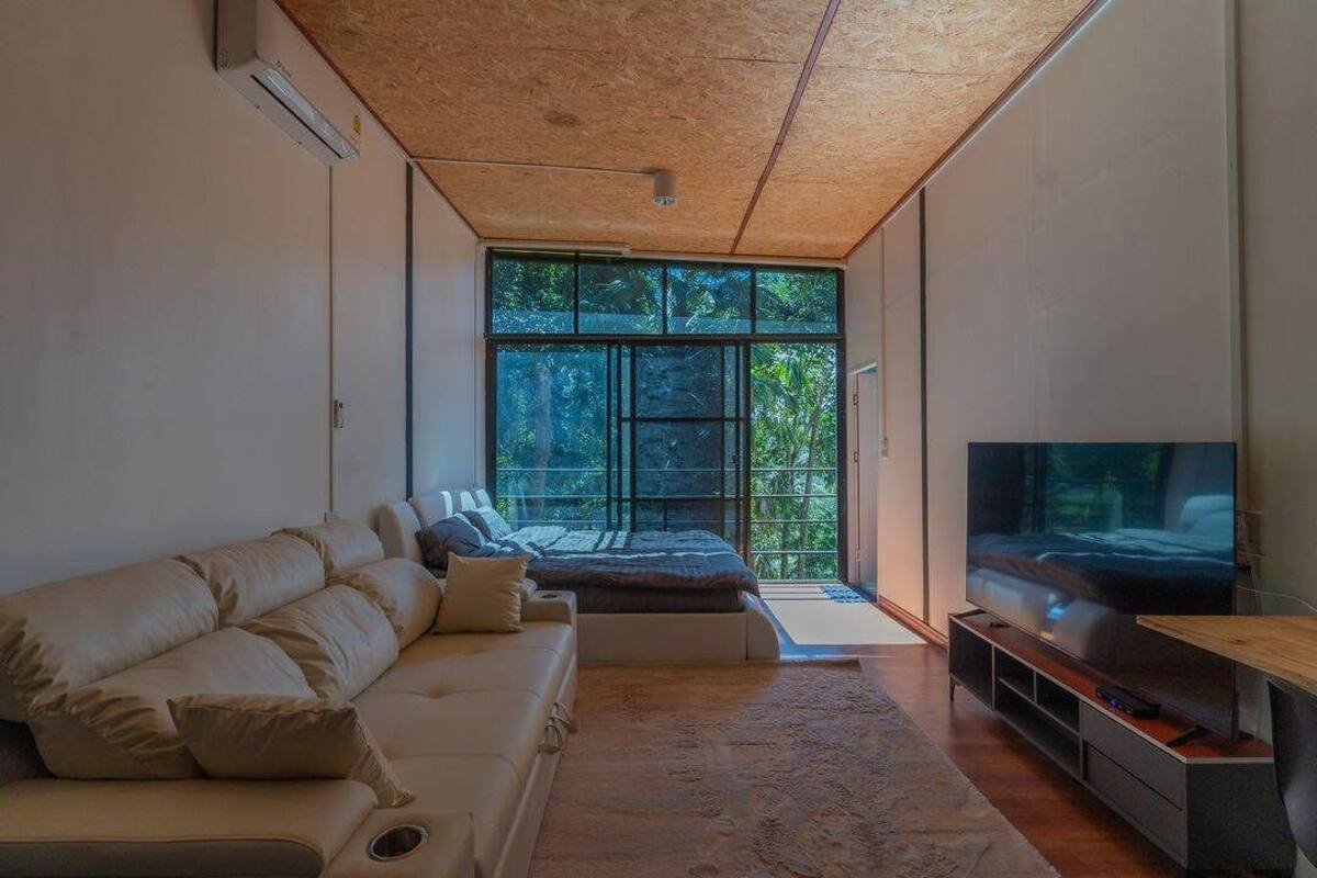 A modern living room with a large window, a sofa, a TV, and a wooden ceiling.
