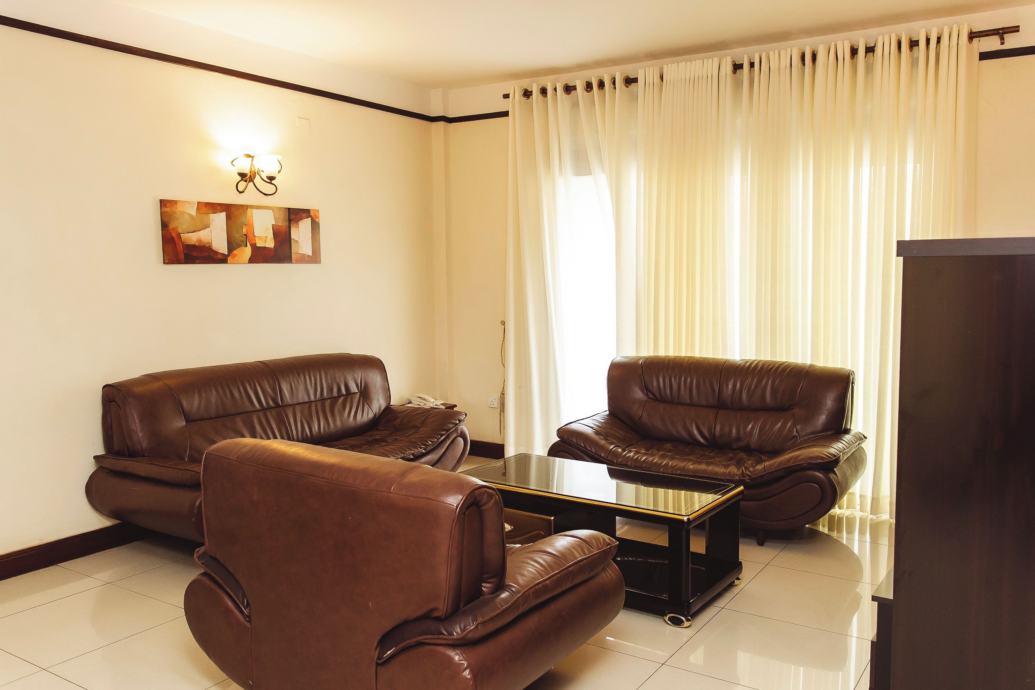 A living room with two brown leather sofas, a glass coffee table, and a flat-screen TV.