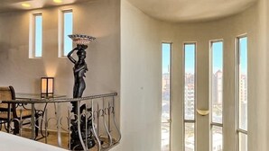 A spacious interior with a curved staircase, a dining area, and large windows offering a city view. - Bella Sirena A701 Penthouse Amazing Ocean Views (Puerto Peñasco)