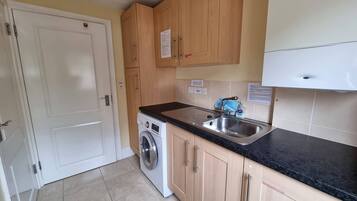 A compact kitchen with a washing machine, a sink, and wooden cabinets.
