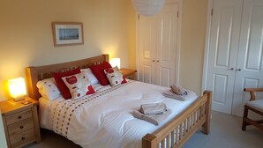 A neatly made bed with a wooden headboard, two bedside lamps, and a framed picture on the wall.