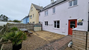 A residential property with a paved patio, a wooden fence, and a red door.