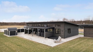 Una casa moderna de dos pisos con un patio cubierto y una parrilla grande al aire libre.