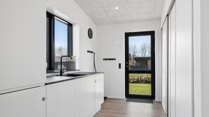 Una cocina moderna con ventana, un lavamanos y una puerta que da a un jardín.