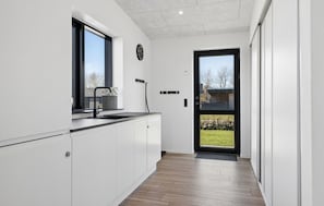 Una cocina moderna con ventana, un lavamanos y una puerta que da a un jardín.