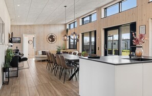 A modern kitchen with a central island, wooden panel walls, and large windows. - 5 bedroom lovely home in Hadsund (Hadsund)