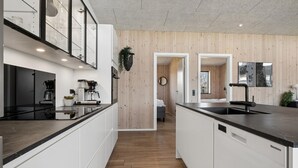 Una cocina moderna con una isla central, electrodomésticos integrados y una pared de madera.