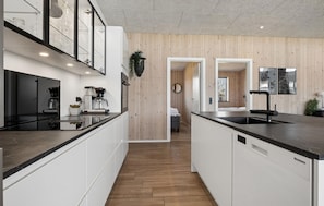 Una cocina moderna con una isla central, electrodomésticos integrados y una pared de madera.