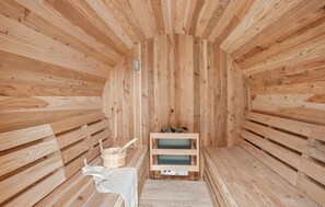 Una sauna con paredes y bancos de madera, un cubo de madera y una toalla.