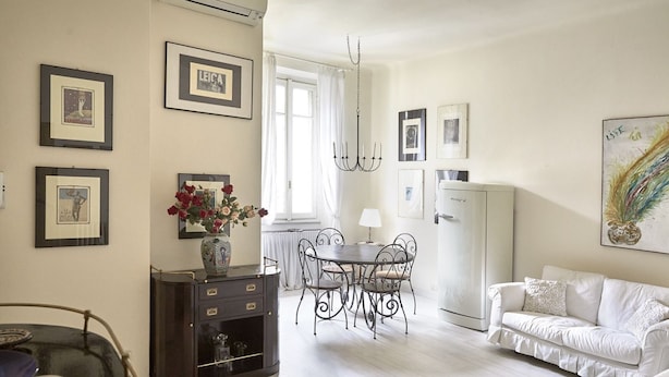 A well-lit room with a dining table, chairs, a sofa, and a cabinet. - Easylife - Jewel of art in Arco della Pace area (Milano)