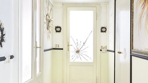 A hallway with a white door, two wreaths, and a decorative wall piece. - Easylife - Jewel of art in Arco della Pace area (Milano)