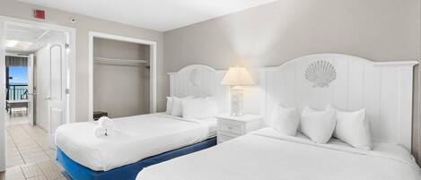 A hotel room with two beds, a walk-in closet, and a view of the beach.