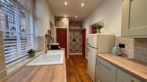 Una cocina moderna con encimera de madera, un lavamanos integrado y un refrigerador.
