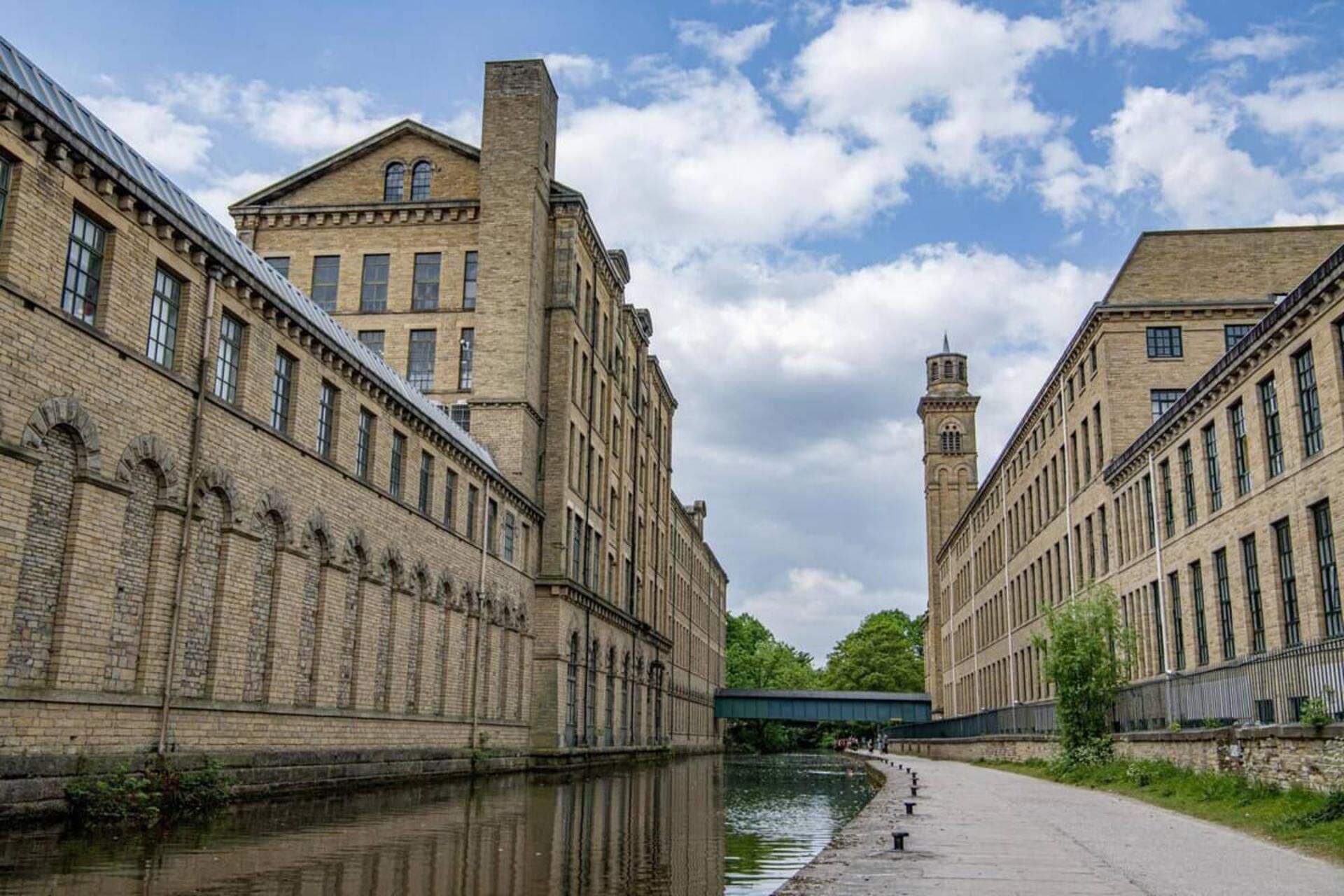 A canal with buildings on either side, a bridge, and a clear sky.