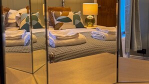 Una habitación de hotel con cama, almohadas, lámpara y toallas.