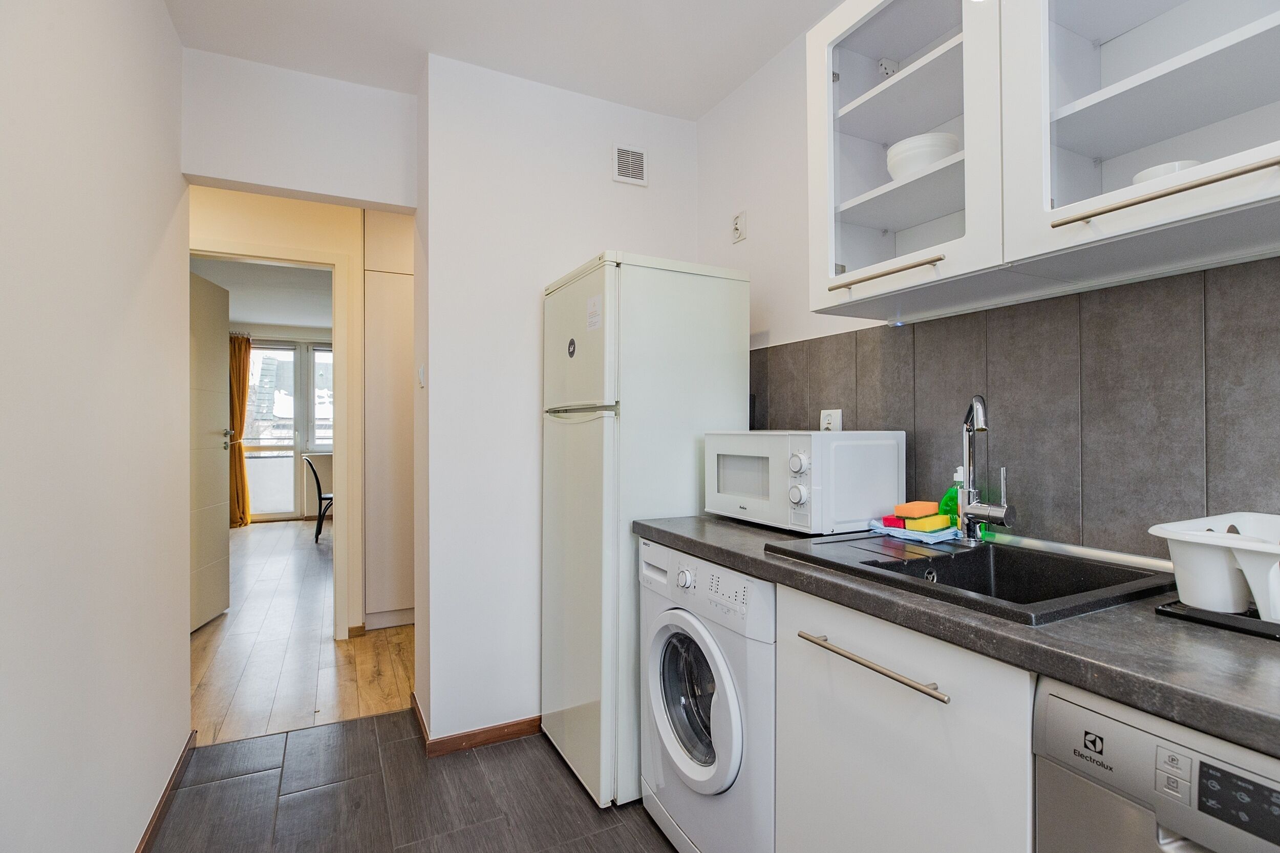 A compact kitchen with a washing machine, microwave, and dishwasher.