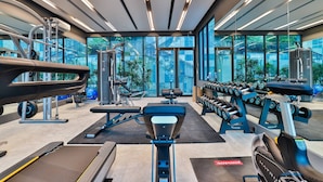 Une salle de sport moderne équipée de machines de cardio, de bancs de musculation et d’haltères.