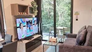 Un salon équipé d’un téléviseur à écran plat, d’un canapé, d’une table basse et d’un coin repas avec une table et des chaises.