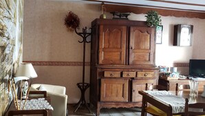Un salon comprenant un meuble en bois, un canapé, une table et un téléviseur.