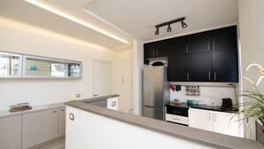 A modern kitchen with white cabinets, a stainless steel refrigerator, and a countertop with various kitchen items. - Appartamento Giada (Padenghe sul Garda)
