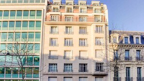 A multi-story building with a mix of architectural styles, including a modern glass facade and traditional balconies. - Bright Etoile /  Bright 2 bed close to Eiffel Tower Arc the Triomphe et Champs E (Paris)
