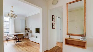 A spacious living area with a dining table, a chandelier, and a large mirror. - Bright Etoile /  Bright 2 bed close to Eiffel Tower Arc the Triomphe et Champs E (Paris)