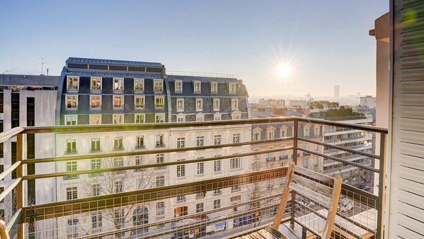 A balcony with a view of a cityscape, including a building with a blue roof and a white facade. - Bright Etoile /  Bright 2 bed close to Eiffel Tower Arc the Triomphe et Champs E (Paris)