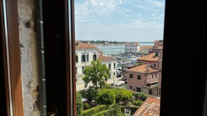 Janela com vista para uma paisagem urbana costeira, incluindo edifícios e um corpo de água.