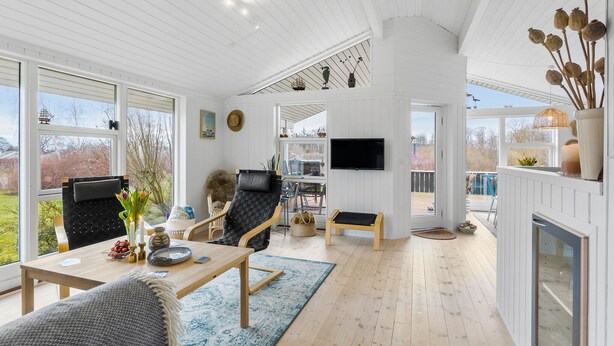 Un salon spacieux doté d’un grand téléviseur, de sièges confortables et offrant une vue sur l’extérieur.