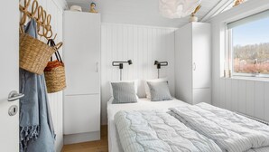 Une chambre à coucher avec un lit, deux tables de chevet, une armoire et une fenêtre donnant sur un beau paysage.