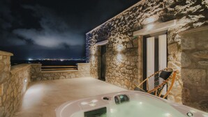 Een stenen gebouw met een hottub en uitzicht op de stad 's nachts.