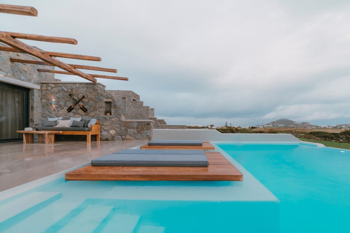 A poolside area with wooden loungers and a stone wall.
