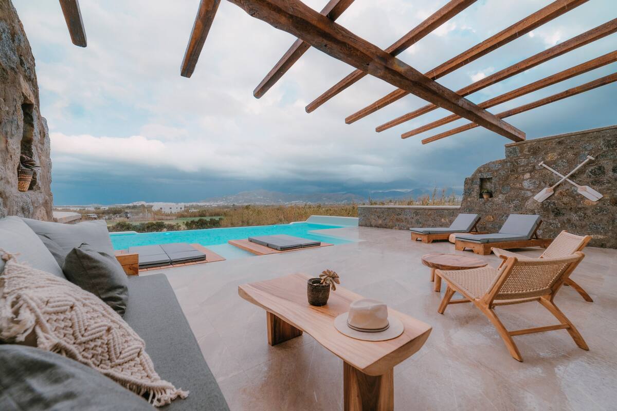 A rooftop terrace with a pool, lounge chairs, and a wooden table.