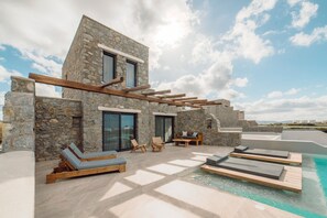 A modern stone building with a pool, wooden loungers, and a pergola. - Naxos Privilege Villas (Naxos)