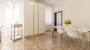 A modern kitchen with a granite countertop, white cabinets, and a stainless steel range hood. There is a small island with a sink and a white chair. - Dolcevita Apartments N. 496 (Venice)