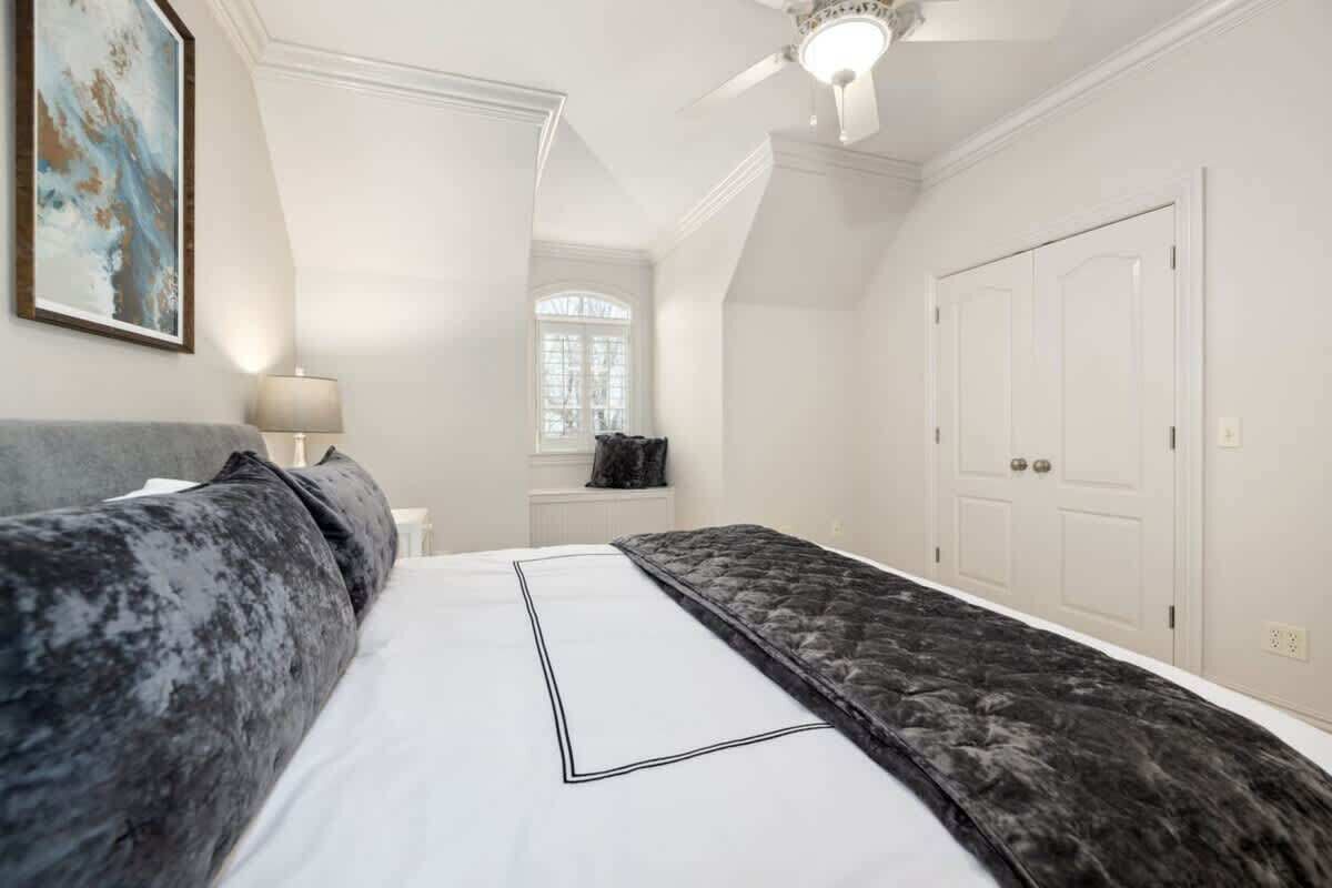 A bedroom with a bed, a nightstand, a lamp, a window, and a door.