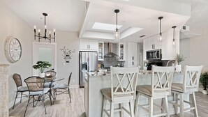 Une cuisine moderne avec des meubles blancs, un îlot central et des luminaires suspendus.