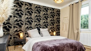 A bedroom with a bed, a desk, and a wall with a leaf pattern. - Ty Mamm, Petit Cocon Breton à 2 pas de la Plage (Plouescat)