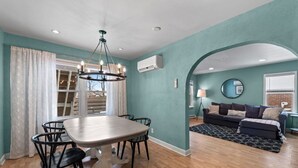A dining area with a table and chairs, a chandelier, and a window with curtains.