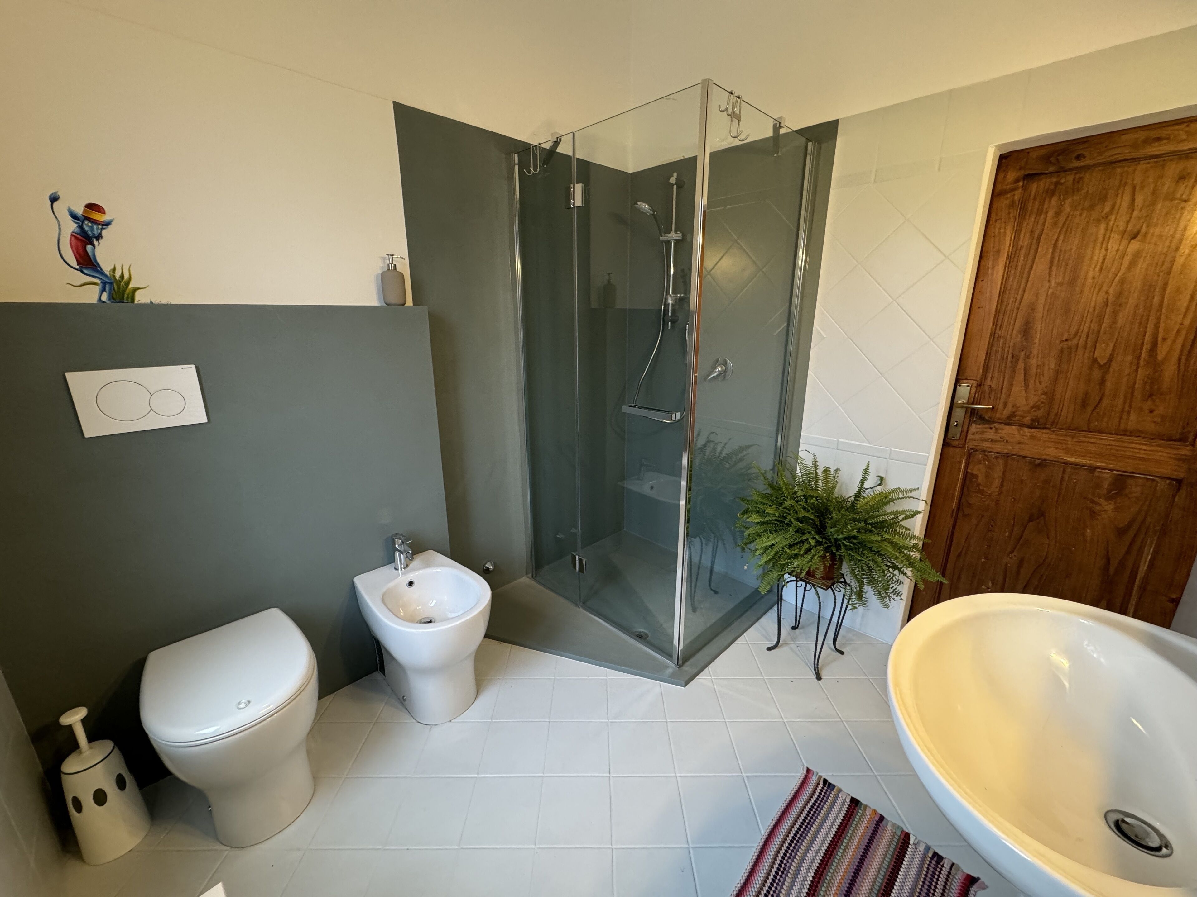 A modern bathroom with a glass-enclosed shower, a toilet, and a large sink.
