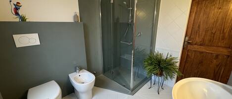 A modern bathroom with a glass-enclosed shower, a toilet, and a large sink.