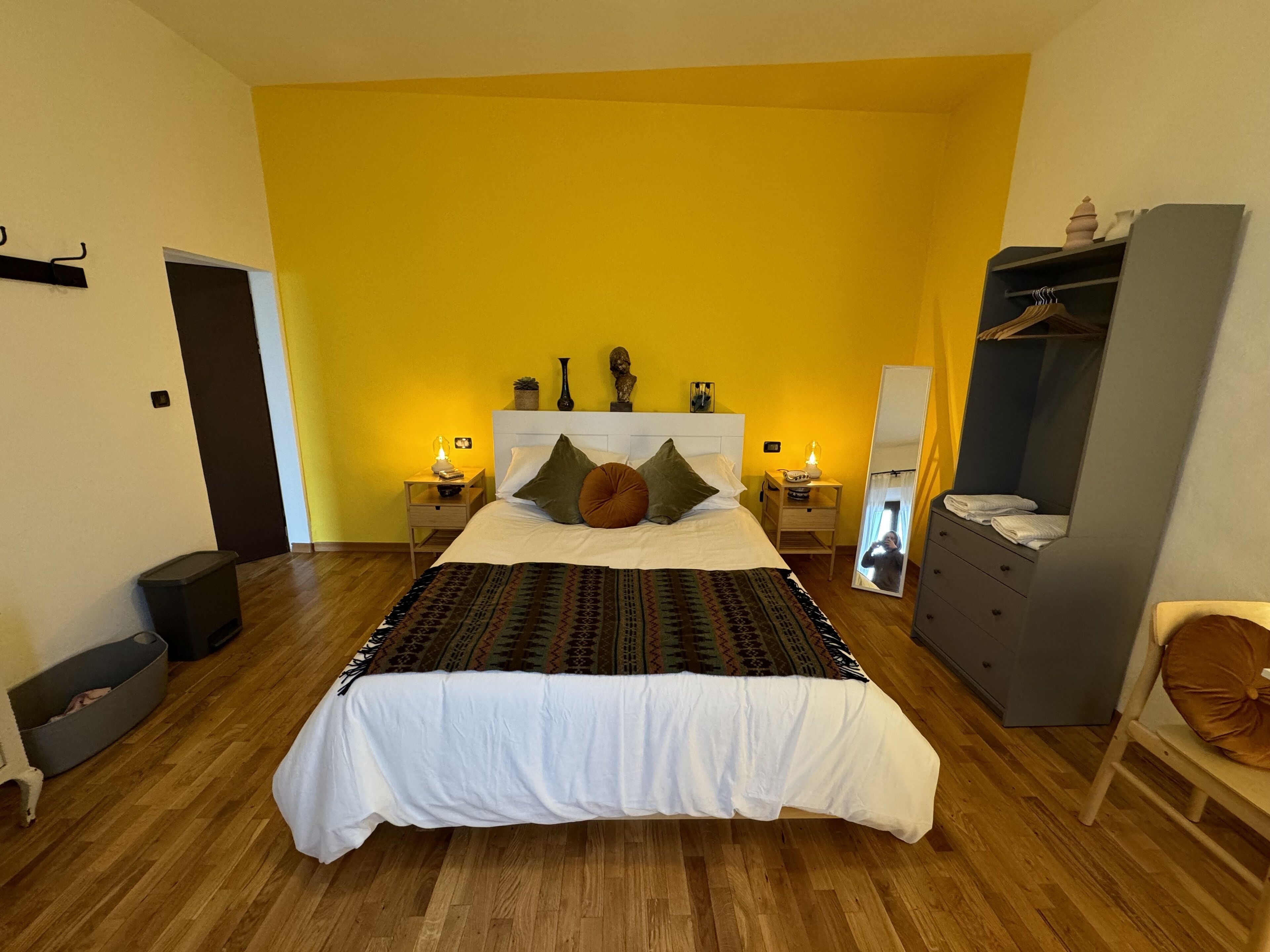 Une chambre à coucher avec un grand lit, deux tables de chevet avec des lampes, une armoire et un miroir.